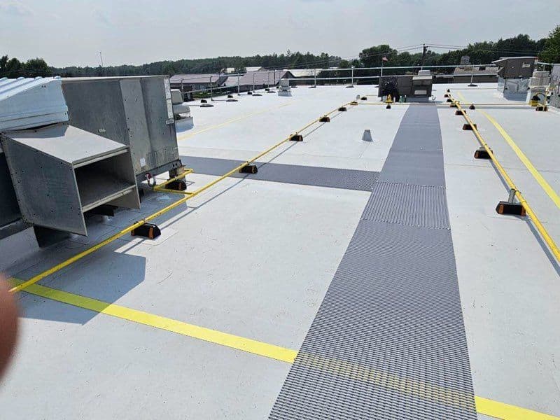 Flat commercial rooftop with HVAC units, safety yellow lines, and textured walkways.